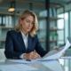 Femme d'affaires en costume bleu examine des documents financiers